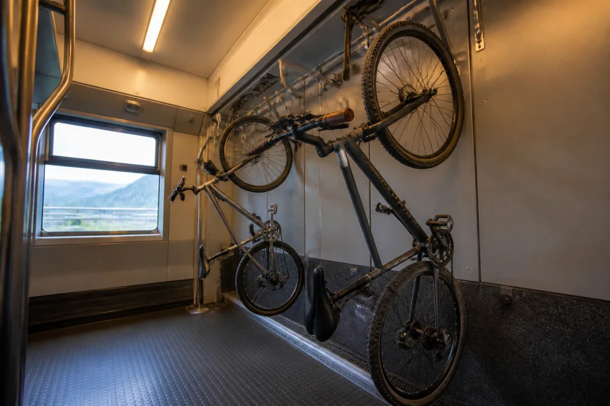 Vélo suspendu par la roue avant à un crochet dans l’espace vélo d’une rame, lumière douce de fenêtre